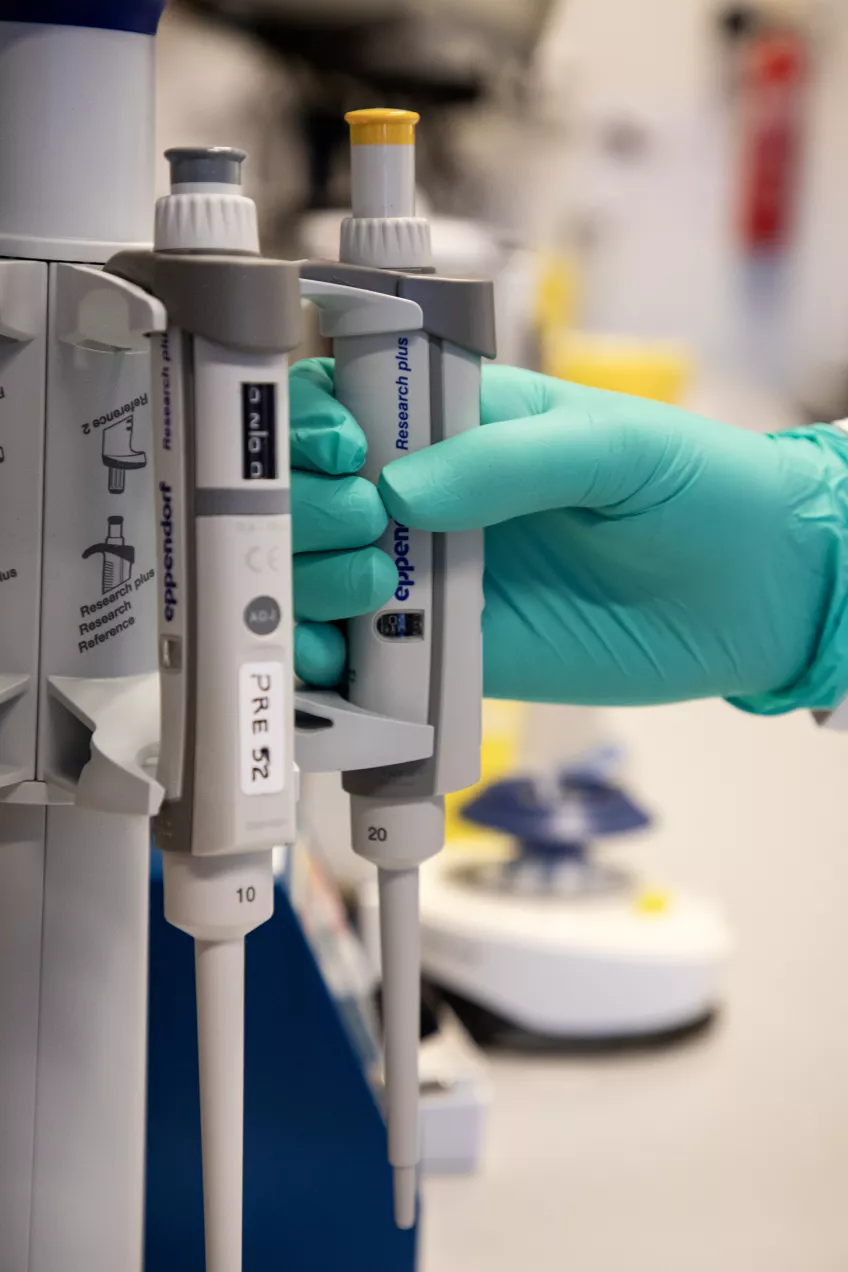 Scientist reaching for a pipette.